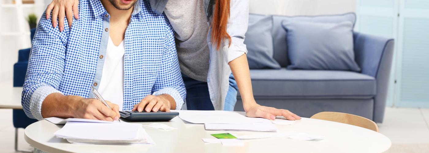 Man and woman looking at calculator. 