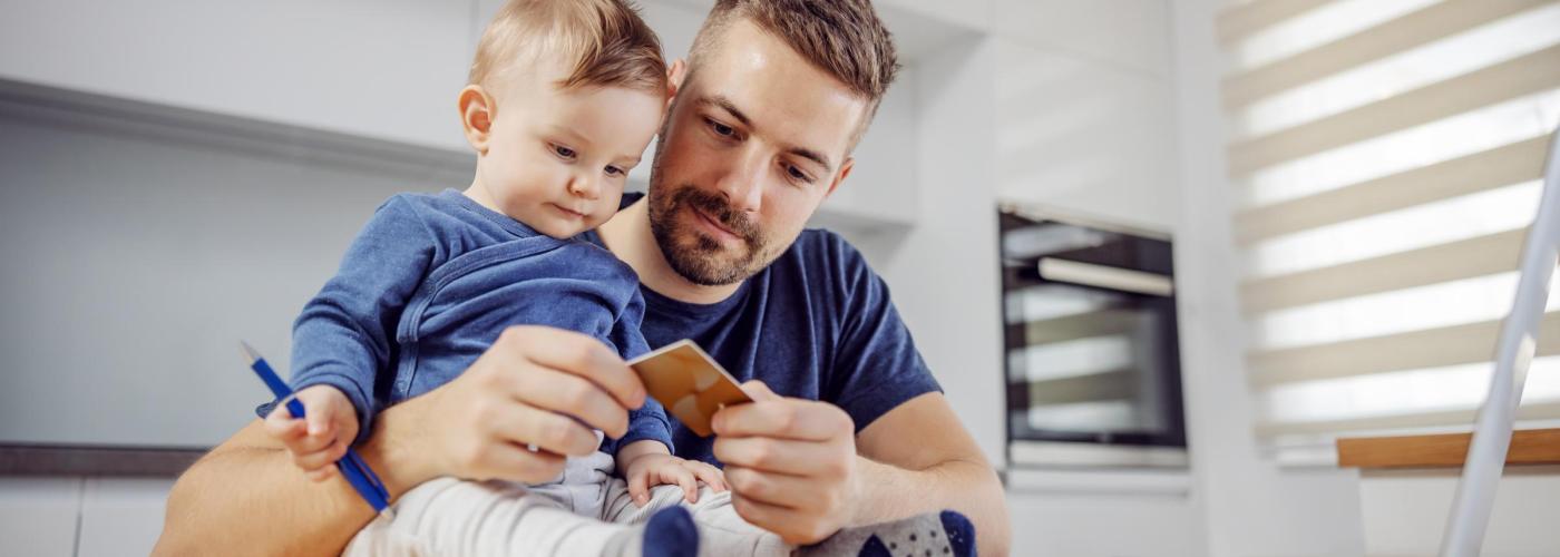 Father and baby looking at credit card to pay bill on computer. 