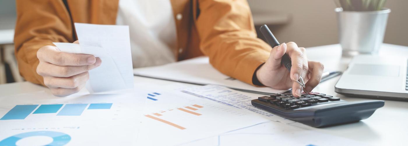 Woman at a calculator looking at charts. 