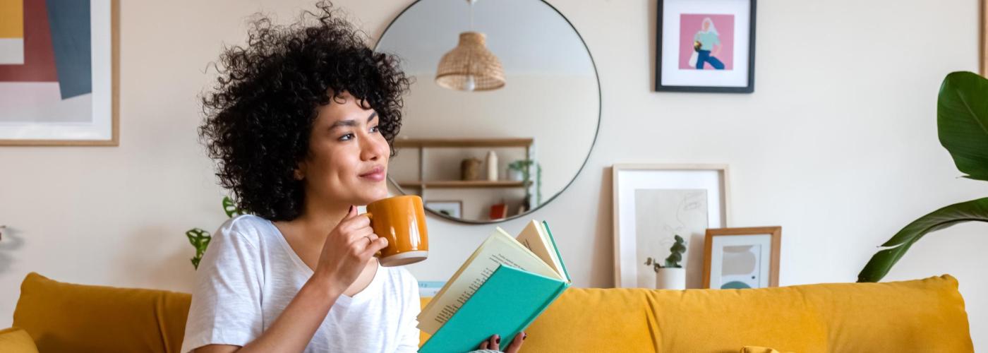 Woman reading on yellow couch. 