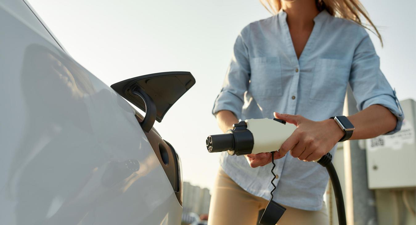 Woman plugging in her electric vehicle.